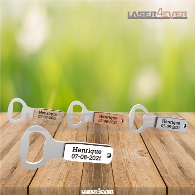 Abridores de garrafas metálicos com etiquetas personalizadas com nome e datas em fundo de madeira.