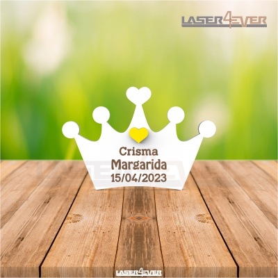 Peça decorativa coroa branca com texto gravado colocada sobre superfície de madeira