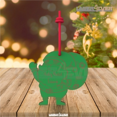 Enfeite Natal verde boneco com cordão vermelho sobre madeira com árvore de Natal ao fundo