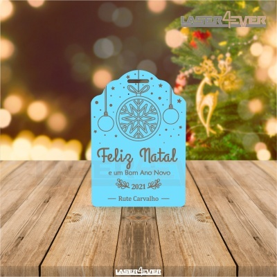 Cartão decorativo azul com texto de Natal numa mesa de madeira