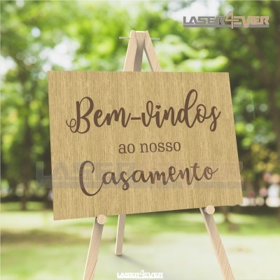 Placa de madeira com texto de boas-vindas a casamento sobre cavalete em ambiente exterior