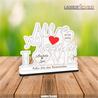 Objeto decorativo 'All you need is LOVE' com corações e texto personalizado, sobre mesa de madeira