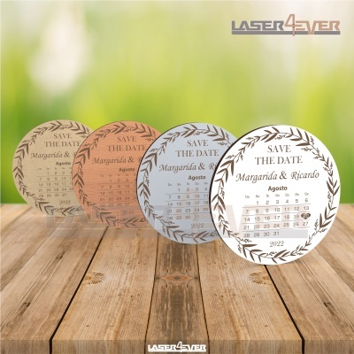 Convites redondos de casamento com calendário do mês de agosto em várias cores sobre mesa de madeira.