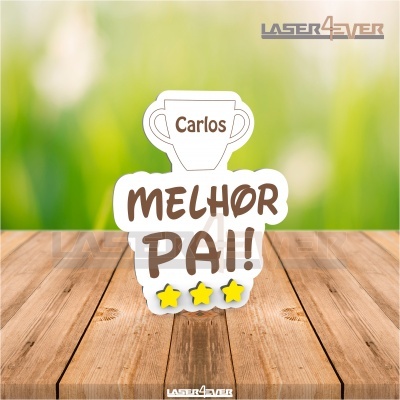 Placa decorativa em acrílico com texto 'MELHOR PAI!' e nome 'Carlos' em fundo verde desfocado