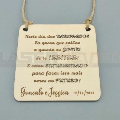 Placa quadrada bege com texto gravado em português pendurada por corda de juta