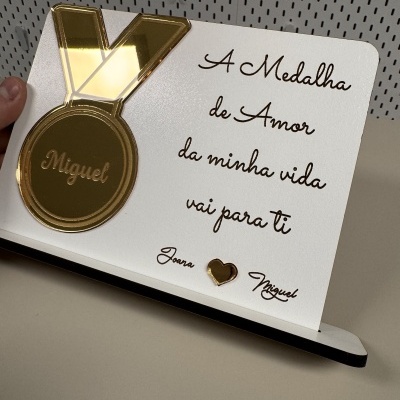 Placa branca com medalha dourada e texto em castanho