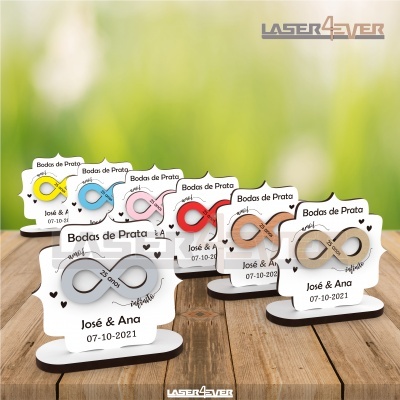 Lembranças Bodas de Prata com símbolo infinito em várias cores sobre mesa de madeira.