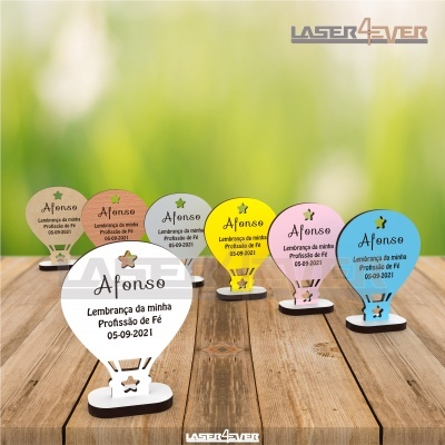 Decorações em forma de balão coloridas de madeira com texto gravado em português sobre uma mesa de madeira