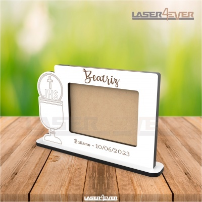 Moldura branca com gravação de batismo e caniço em madeira sobre mesa