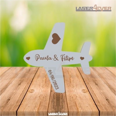 Avião decorativo branco com corações castanhos e texto 'Paula & Filipe' e data '04/06/2023' sobre superfície de madeira