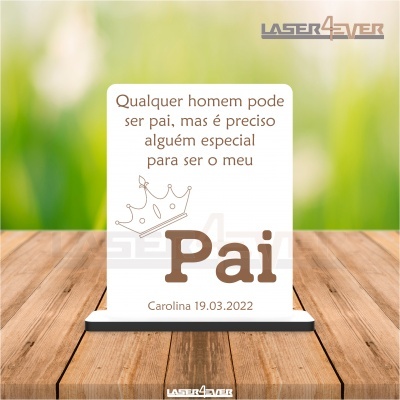 Placa decorativa branca com texto em castanho e base preta sobre madeira clara