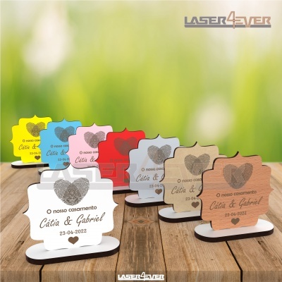 Placas de mesa coloridas em madeira com texto gravado para casamento sobre mesa de madeira