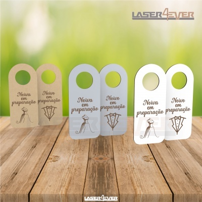 Tags de pendurar em papel castanho claro, cinzento e branco com texto 'Noiva em preparação' e desenho de vestido de noiva sobre mesa de madeira