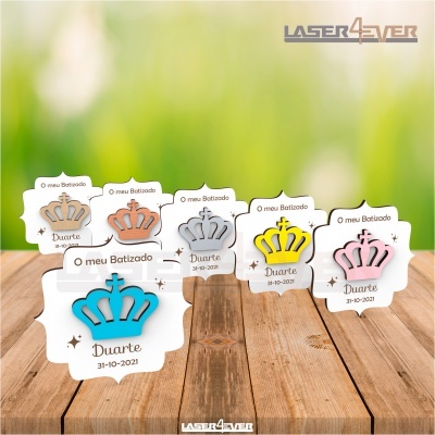 Lembranças de batizado coroa de madeira colorida com texto gravado sobre mesa de madeira