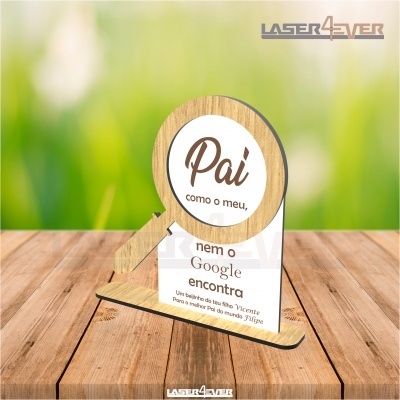 Placa decorativa em madeira e acrílico com mensagem para pai, sobre mesa de madeira com fundo verde desfocado.