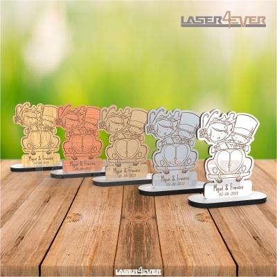 Peças decorativas de madeira e acrílico com casal num carro e texto gravado sobre superfície de madeira