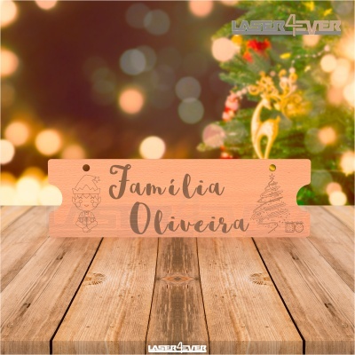 Placa de madeira com texto 'Família Oliveira' e desenhos natalícios em fundo festivo