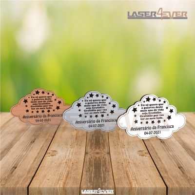 Três placas decorativas em madeira com texto sobre aniversário, em diferentes cores, sobre mesa de madeira.