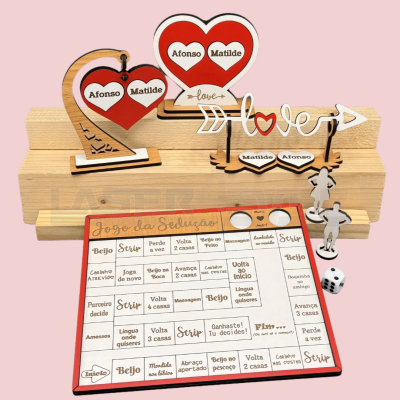 Jogo da Sedução com tabuleiro, peças em madeira decoradas com corações vermelhos e nomes, dados e setas com texto amoroso