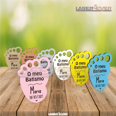 Lembranças em forma de pegada com texto de batismo em várias cores sobre madeira