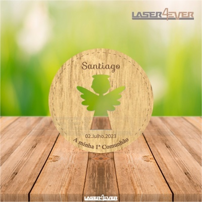 Disco redondo em madeira clara com recorte de anjo e gravura com texto sobre comunhão colocado numa mesa de madeira