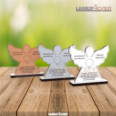Lembranças de batismo em forma de anjo em acrílico castanho, cinzento e branco sobre superfície de madeira.