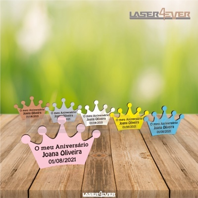 Decorações coloridas em forma de coroa com texto de aniversário sobre mesa de madeira