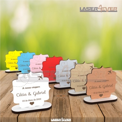 Lembranças de madeira em várias cores com gravação a laser de texto e imagens de avião e coração.