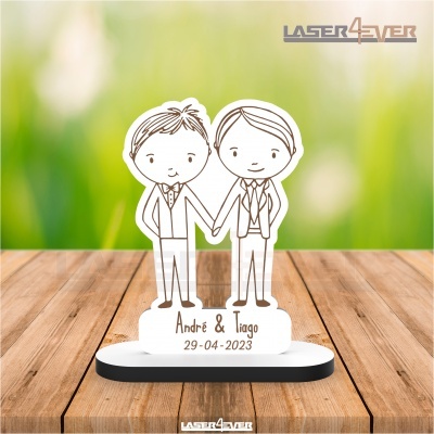 Estatueta acrílica de casal masculino com nomes e data na base sobre mesa de madeira
