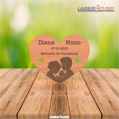 Coração de madeira gravado a laser com texto e silhuetas, sobre mesa de madeira