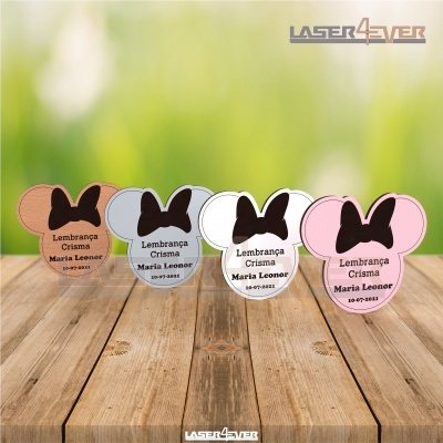 Lembranças de crisma em forma de cabeça de rato com laço em várias cores, sobre mesa de madeira e fundo verde desfocado.