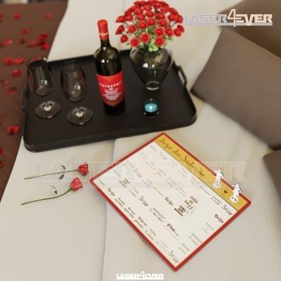 Mesa com tabuleiro preto contendo vinho, copos, vaso com rosas, rosas soltas e menu em madeira num sofá