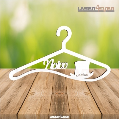 Cabide branco de madeira com texto recortado 'Noivo' e chapéu de cartola com nome 'Cristiano' sobre mesa de madeira