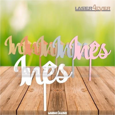 Decorações de madeira com palavra Inês em várias cores sobre mesa de madeira.