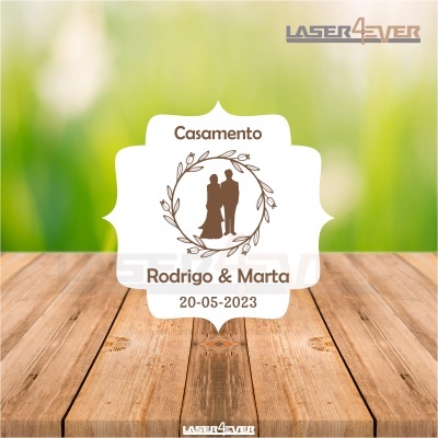 Etiqueta de casamento com texto e silhueta do casal sobre fundo branco e madeira