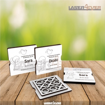 Placares quadrados brancos personalizados com nomes e desenhos infantis e jogo da velha em superfície de madeira.