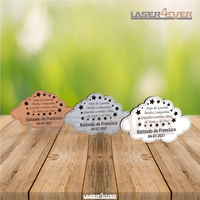 Três suportes em forma de nuvem com texto gravado em três cores diferentes sobre mesa de madeira e fundo verde desfocado.