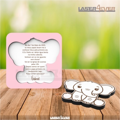 Caixa de madeira rosa com recortes e texto em português, com uma figura de elefante branca ao lado, num fundo verde desfocado