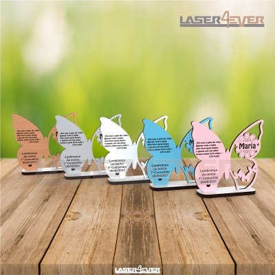 Lembranças em acrílico colorido formato borboleta para 1ª Comunhão sobre mesa de madeira