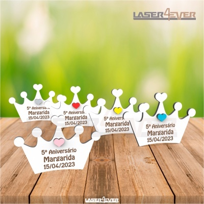 Cinco coroas de madeira branca com texto comemorativo sobre uma superfície de madeira clara