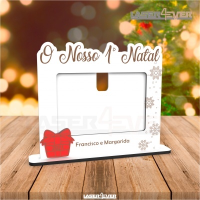 Porta-fotos de madeira branco com texto e decoração natalícia sobre mesa de madeira