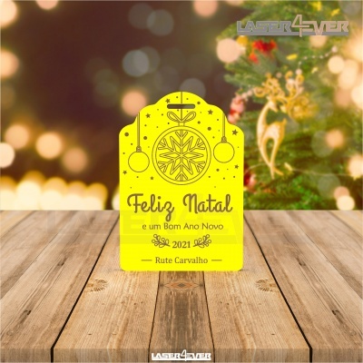 Cartão amarelo de Natal com texto em preto sobre madeira clara e fundo natalício desfocado