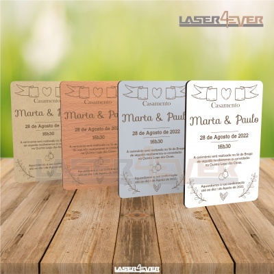 Quatro convites de casamento em papeis coloridos com texto em português sobre madeira