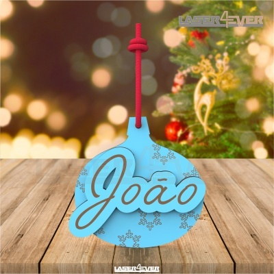Ornamento de Natal azul com nome João pendurado por cordão vermelho sobre mesa de madeira