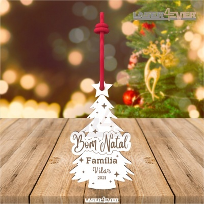 Enfeite de Natal branco em forma de árvore com texto pendurado por cordão vermelho sobre mesa de madeira