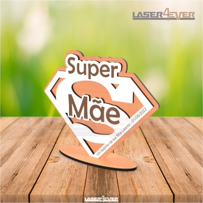 Peça decorativa de madeira com texto Super Mãe em mesa de madeira