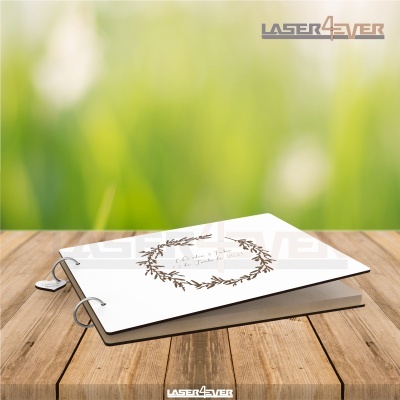 Livro branco decorado com flores castanhas e texto, sobre mesa de madeira