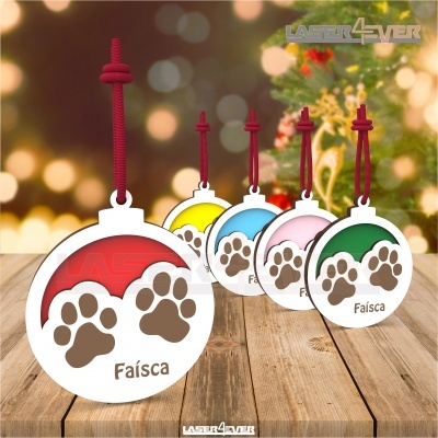 Pendentes redondos coloridos com pegadas castanhas e nome Faísca, sobre mesa de madeira e fundo iluminado