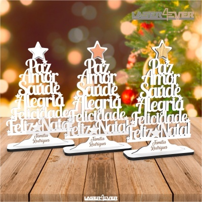 Decorações de Natal de madeira com texto em branco e estrelas coloridas em cima, sobre uma mesa de madeira com luzes de Natal ao fundo.