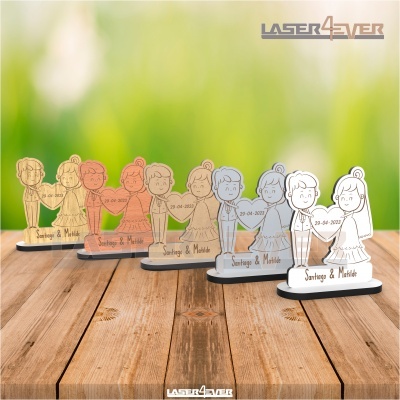 Figuras decorativas acrílicas de casal de noivos em várias cores sobre mesa de madeira